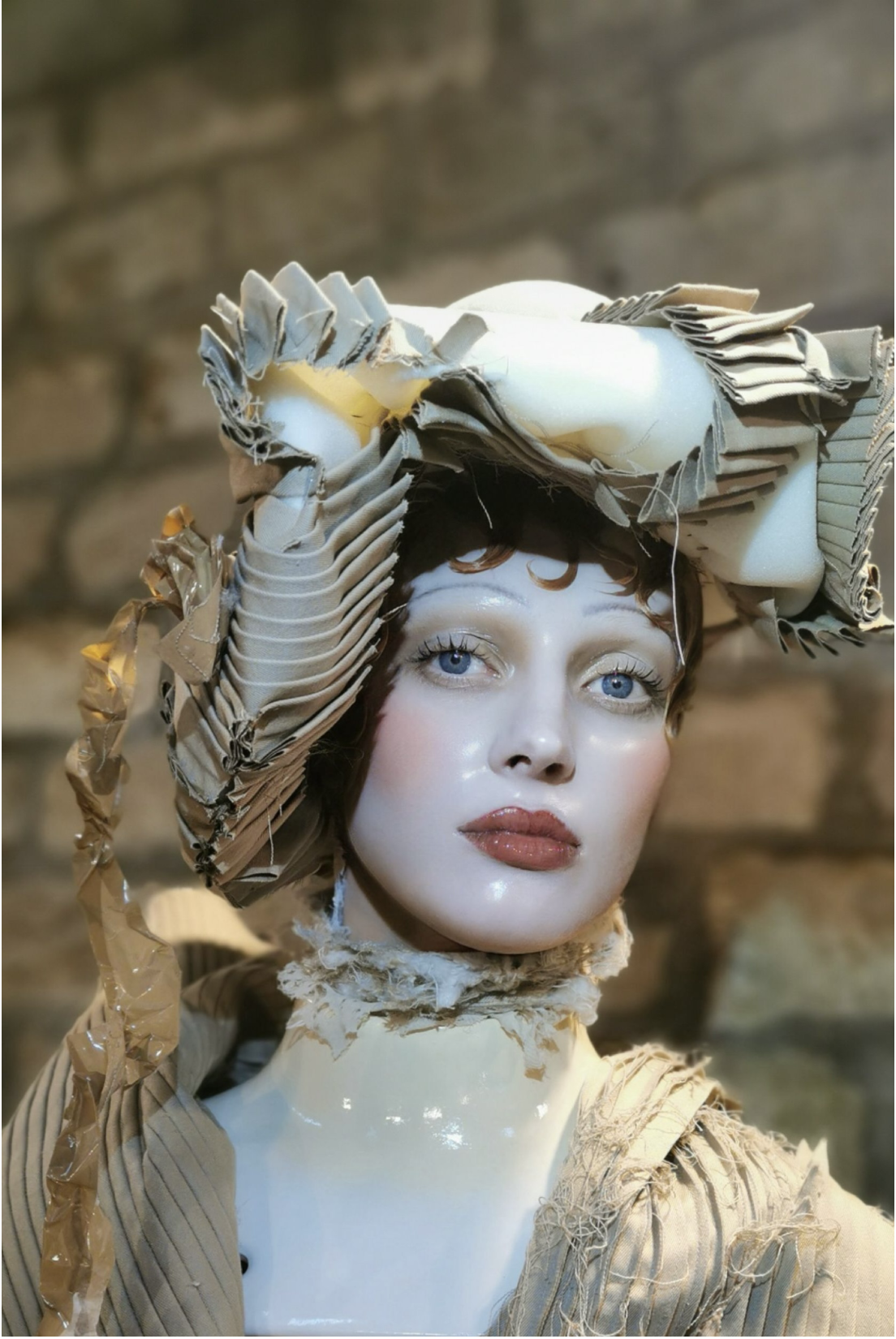Runway look with glassy porcelain-doll skin and a sculptural pleated headpiece