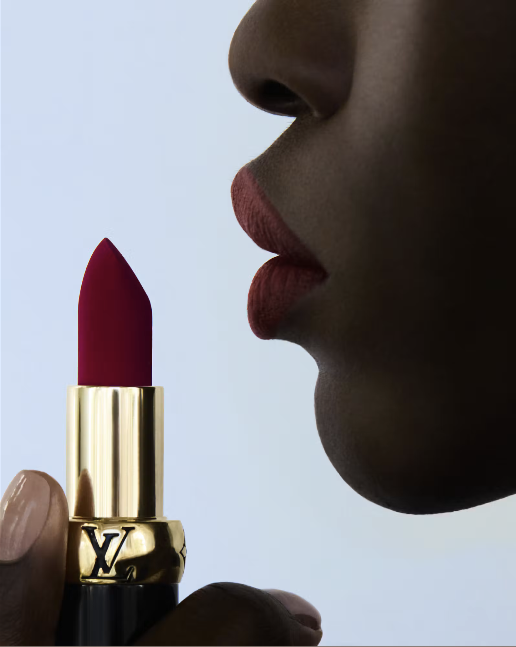 Profile of matte lips beside a gold La Beauté Louis Vuitton lipstick